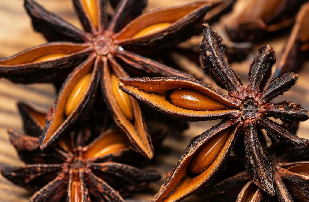 Detailed macro image of star anise spices on a natural wooden background, highlighting textures.