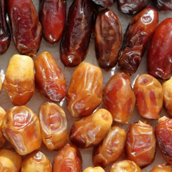 High-resolution image of different varieties of dried dates arranged in rows, showing texture and color.